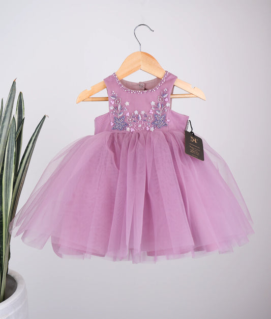 Front view of pastel lavender tulle net handworked birthday frock against plain background