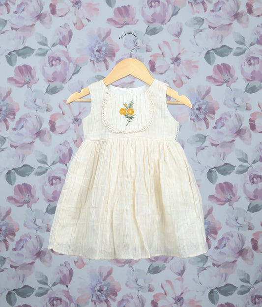 Off-white sleeveless baby dress with yellow floral embroidery and pleated frock on hangers.