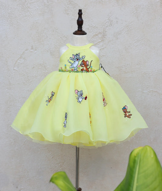 Front view of yellow plain organza tom and Jerry-themed birthday dress for baby girl