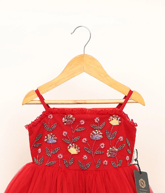 Back view of a handworked tulle net birthday frock against plain background