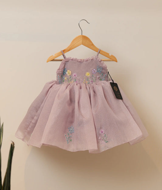 Front view of pastel lavender crush organza flower-themed birthday frock against plain background