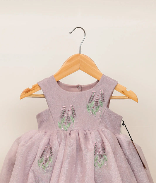 Close view of pastel lavender crush organza floral embroidery with handwork birthday frock against plain background