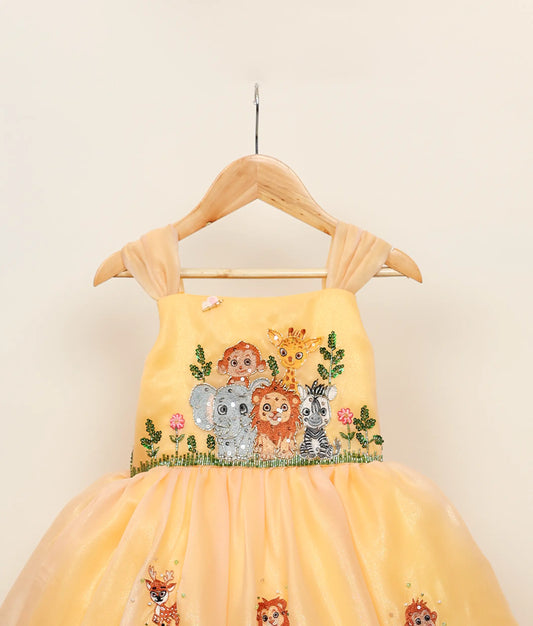 Close view of golden yellow jungle-themed birthday gown against plain background
