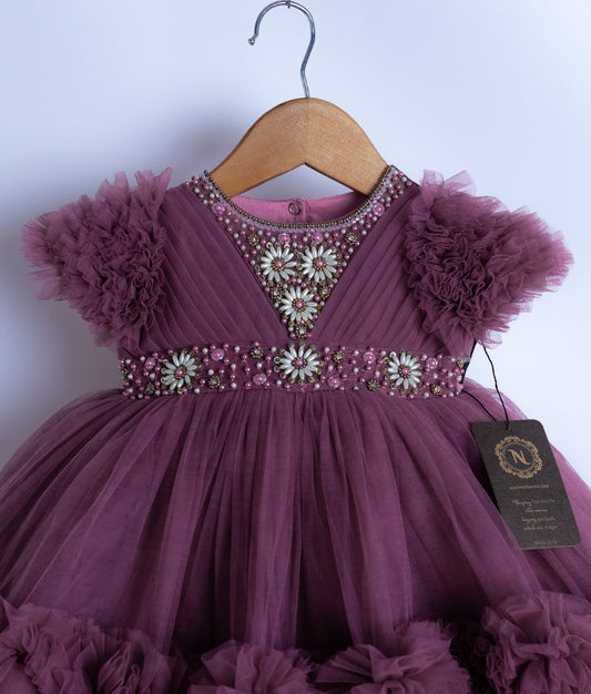 Close view of a pastel lavender tulle net frock with short puffy sleeves displayed on a hanger.