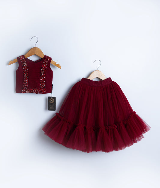 A maroon tulle net handworked skirt and top set displayed against a white background.