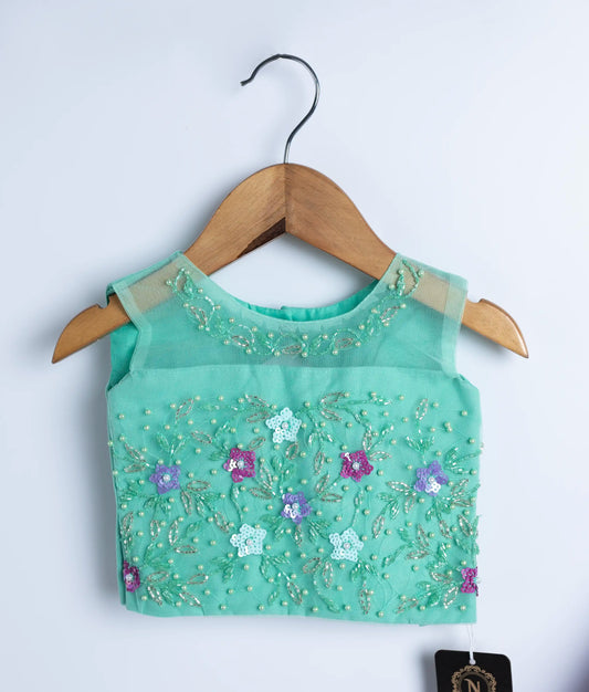 Close view of an ocean green handworked top displayed on hangers against a white background.