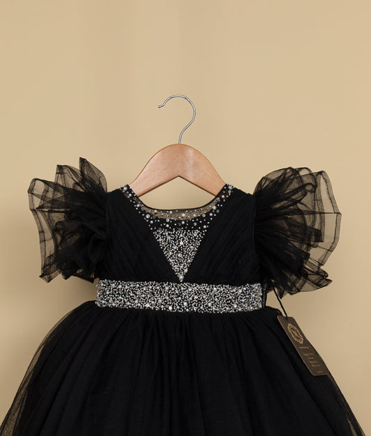 Close view of a black tulle net birthday frock displayed on a hanger.