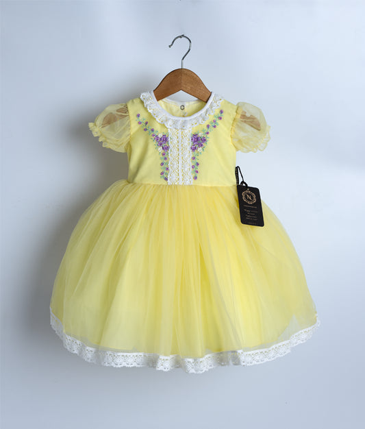 A pastel yellow tulle net floral embroidery displayed on a hanger.