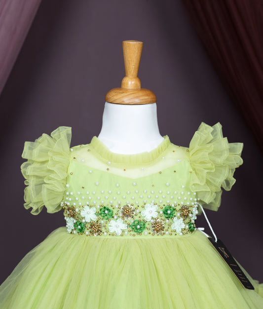 Lime green baby girl party dress with floral bead embroidery and pearl details on bodice, ruffled sleeves, and soft net fabric – displayed on mannequin.