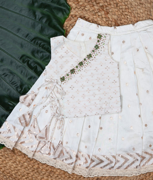 Off-white dress with gold details on a woven mat surface.