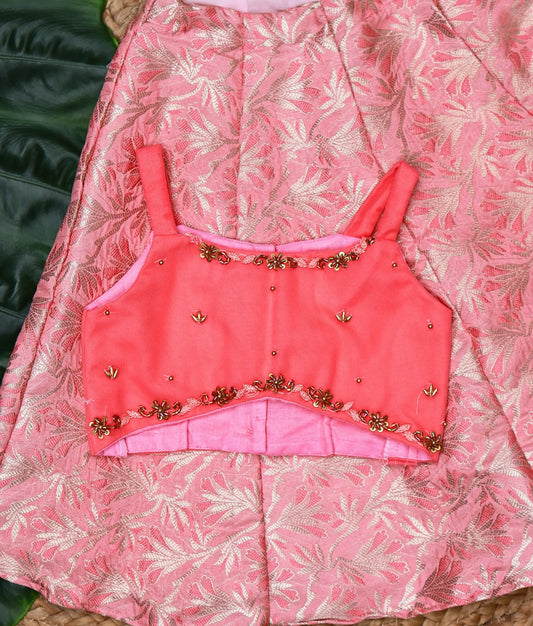 Close view of a stylish pink kids lehenga set with a floral brocade skirt and an embellished sleeveless top.