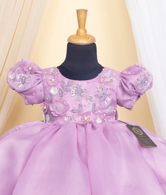 Close view of an lavender dress with floral and sequin details on a mannequin against a beige background.