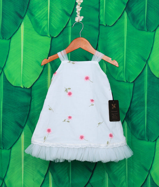 White baby girl frock with pink floral embroidery and net frill hem, displayed on a wooden hanger.