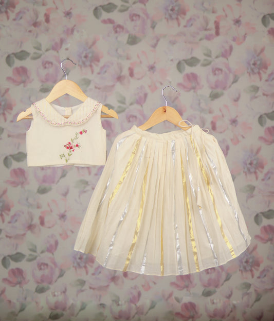 off-white baby girl's festive skirt set with a floral embroidery top and a golden Kasav line skirt.