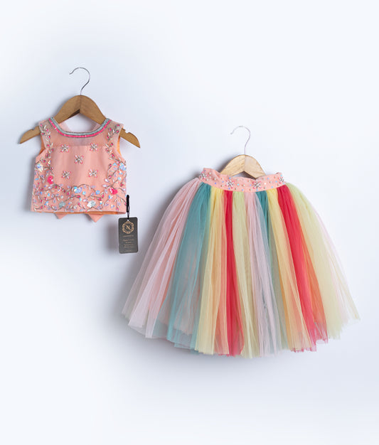 A peach top with multicolor tulle skirt, displayed on hangers against a white background.