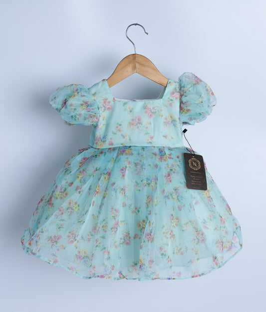 Light blue printed organza frock hanging on a wooden hanger.