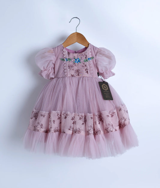 A lavender floral embroidered frock with short puffed sleeves and multiple layers of tulle frills, displayed on a hanger.