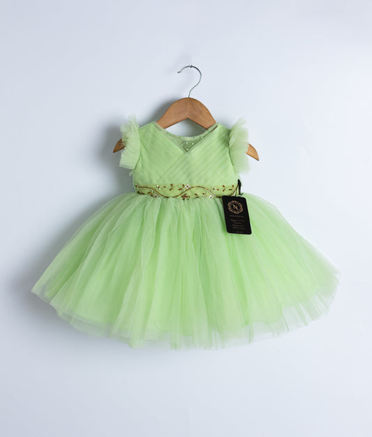 Pastel green tulle net frock displayed on a hanger.