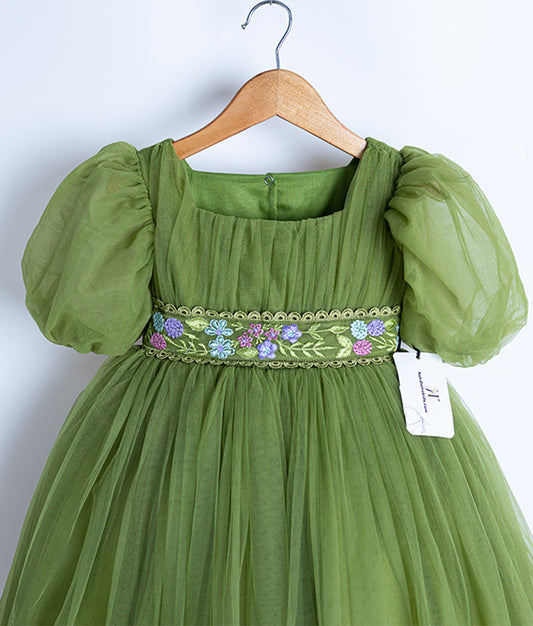 Close view of olive green tulle net embroidery frock hanging on a wooden hanger.