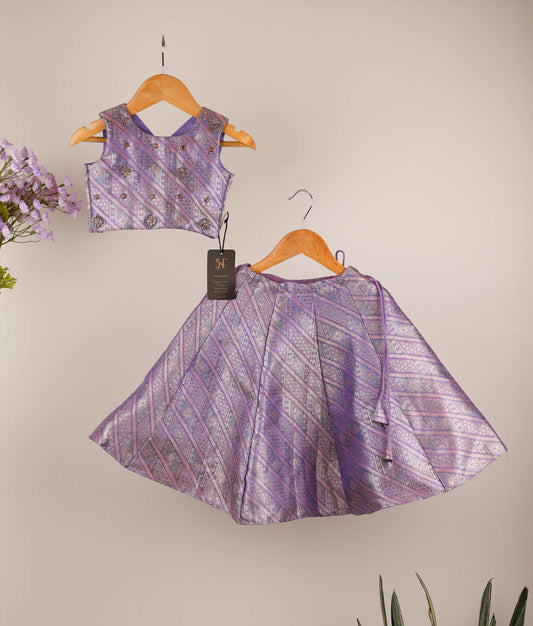 Lavender traditional outfit with skirt and top on hangers against an ash background.