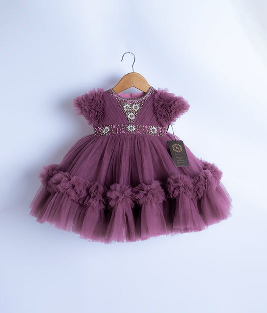 A pastel lavender tulle net frock with short puffy sleeves displayed on a hanger.