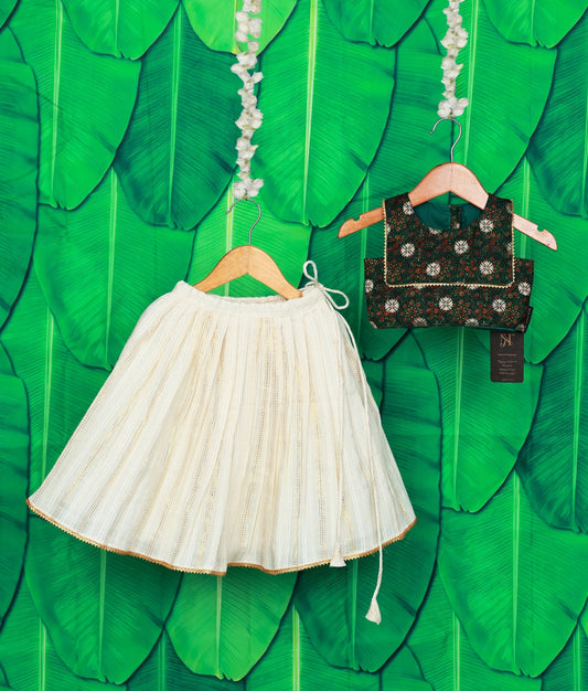 Traditional off-white skirt and green floral top set on a green leaf background.