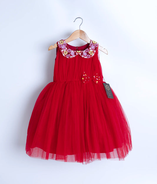 A red tulle net frock displayed on a wooden hanger.
