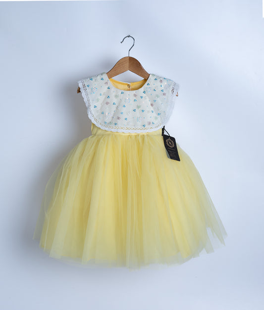 An off-white and yellow frock displayed on a hanger.
