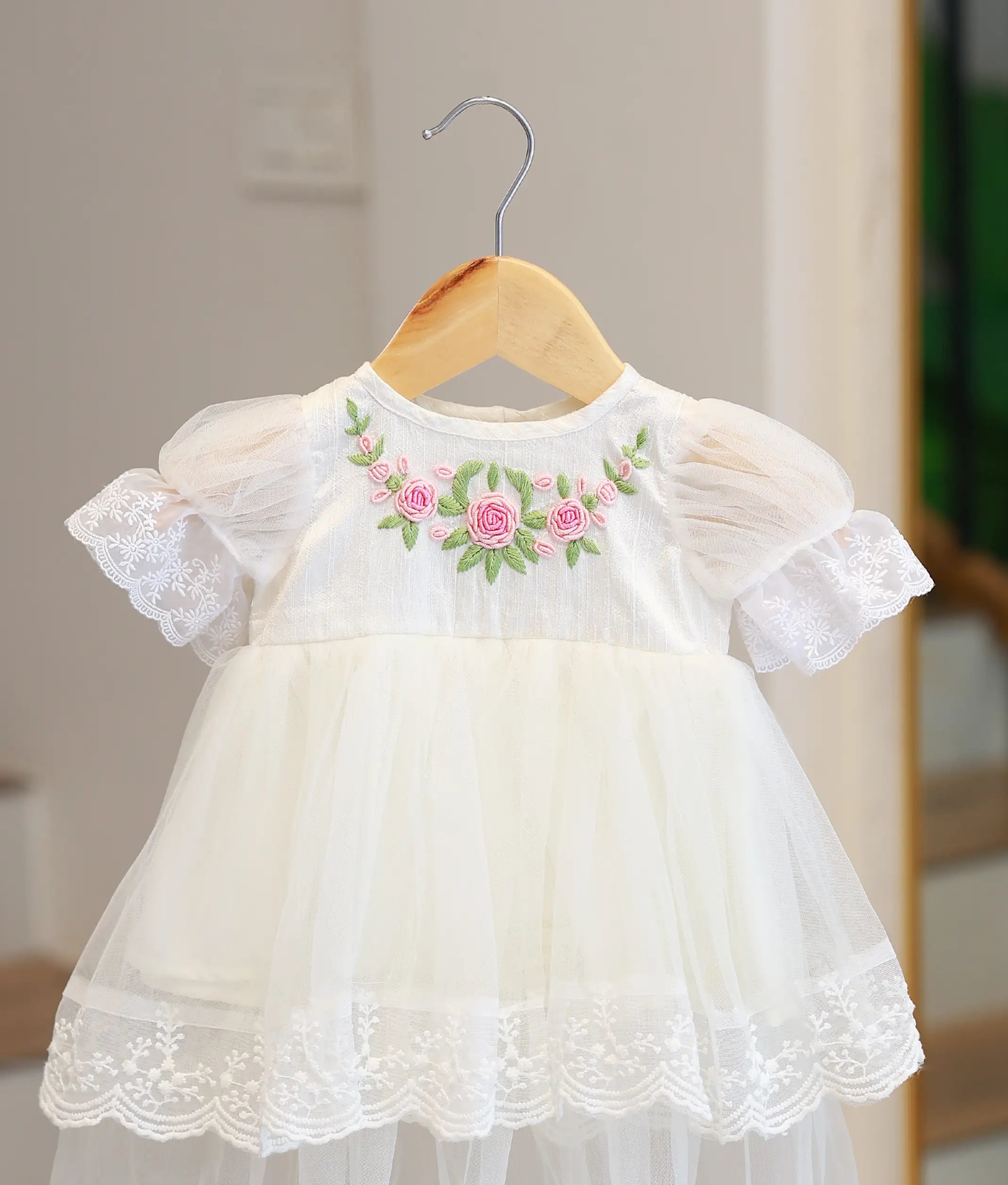 Close-up of hand-embroidered floral neckline and scalloped lace hem on a designer baby baptism gown.