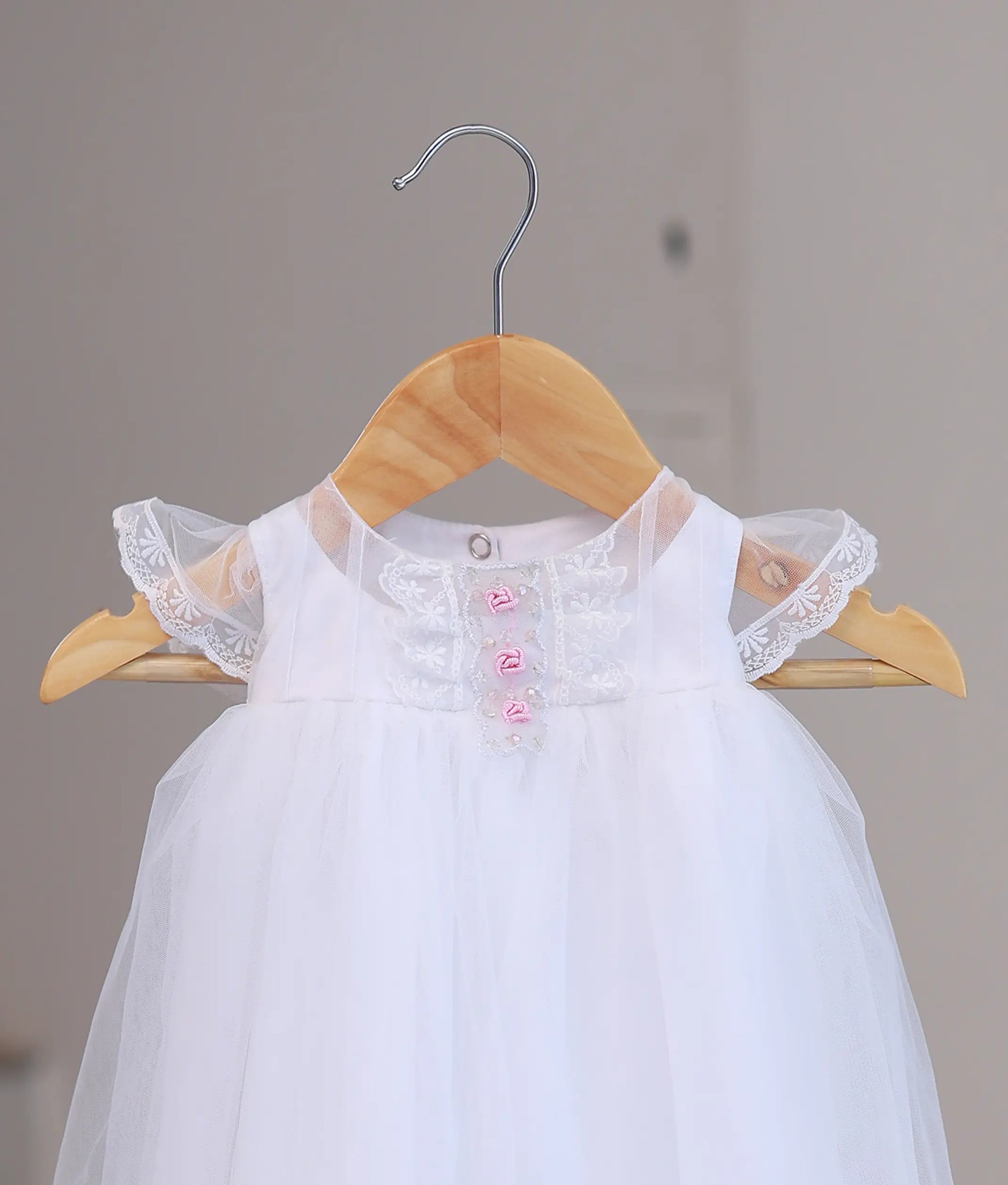 Close-up of premium hand-stitched floral lace and pearl work on a designer boutique baptism dress for infants.