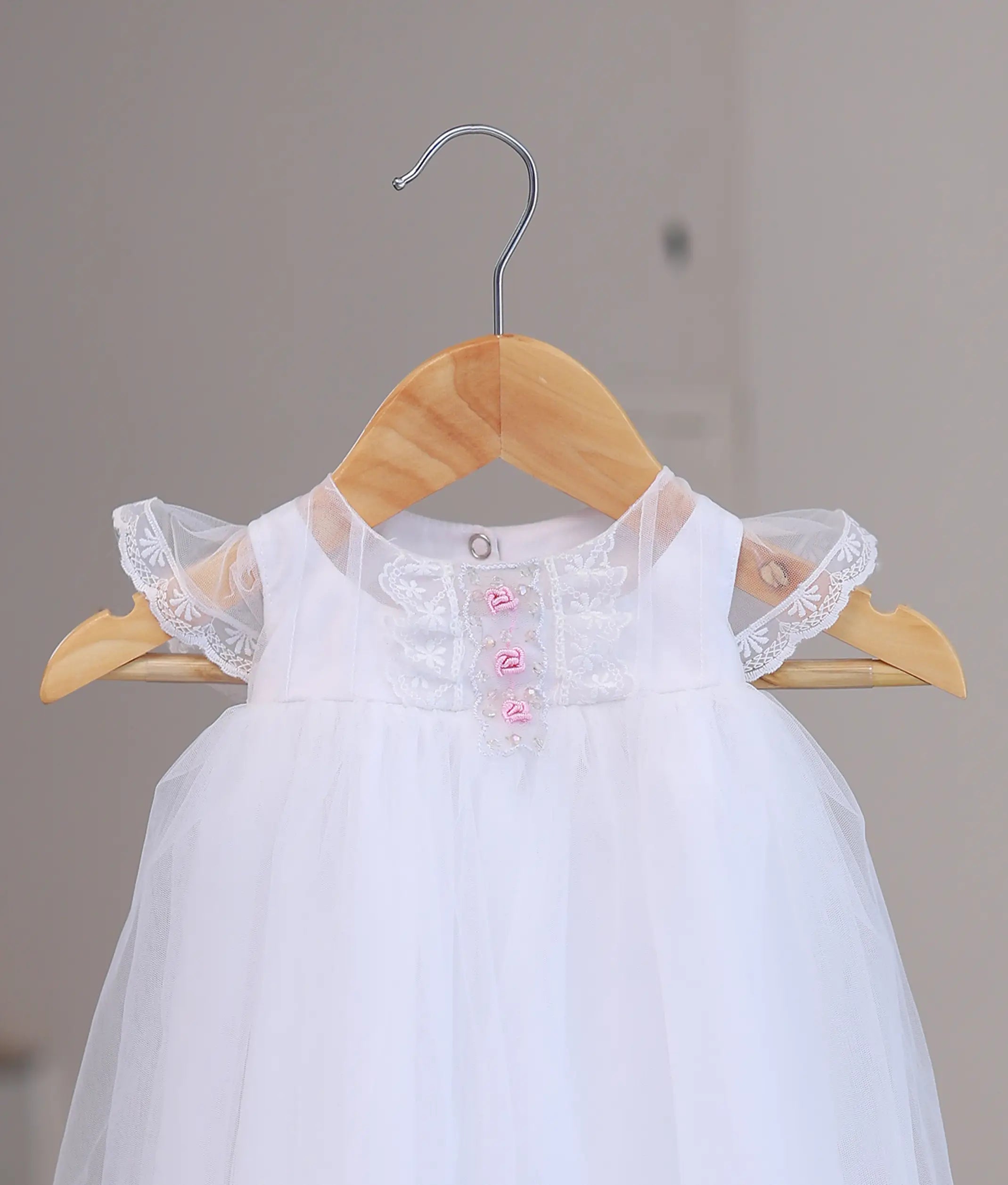 Close-up of premium hand-stitched floral lace and pearl work on a designer boutique baptism dress for infants.