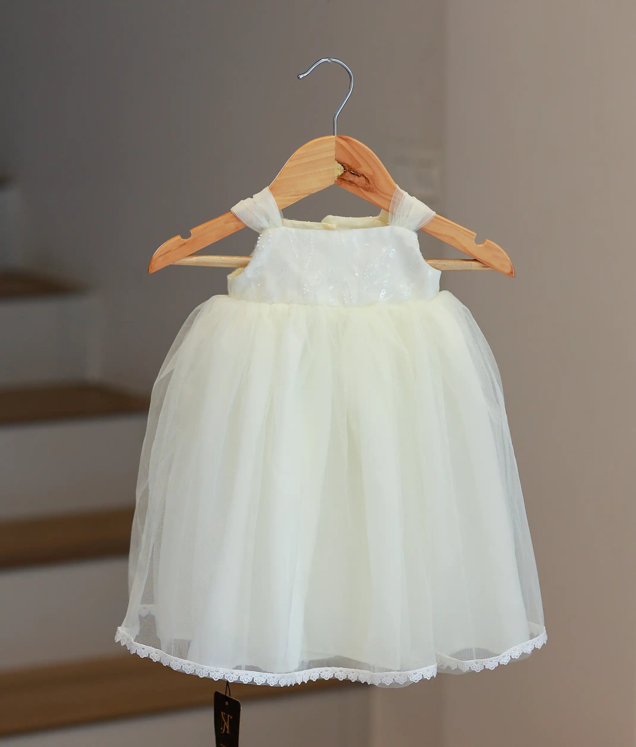 Front view of an off-white handworked tulle baptism gown for baby girls with floral embroidery and puffed sleeves.