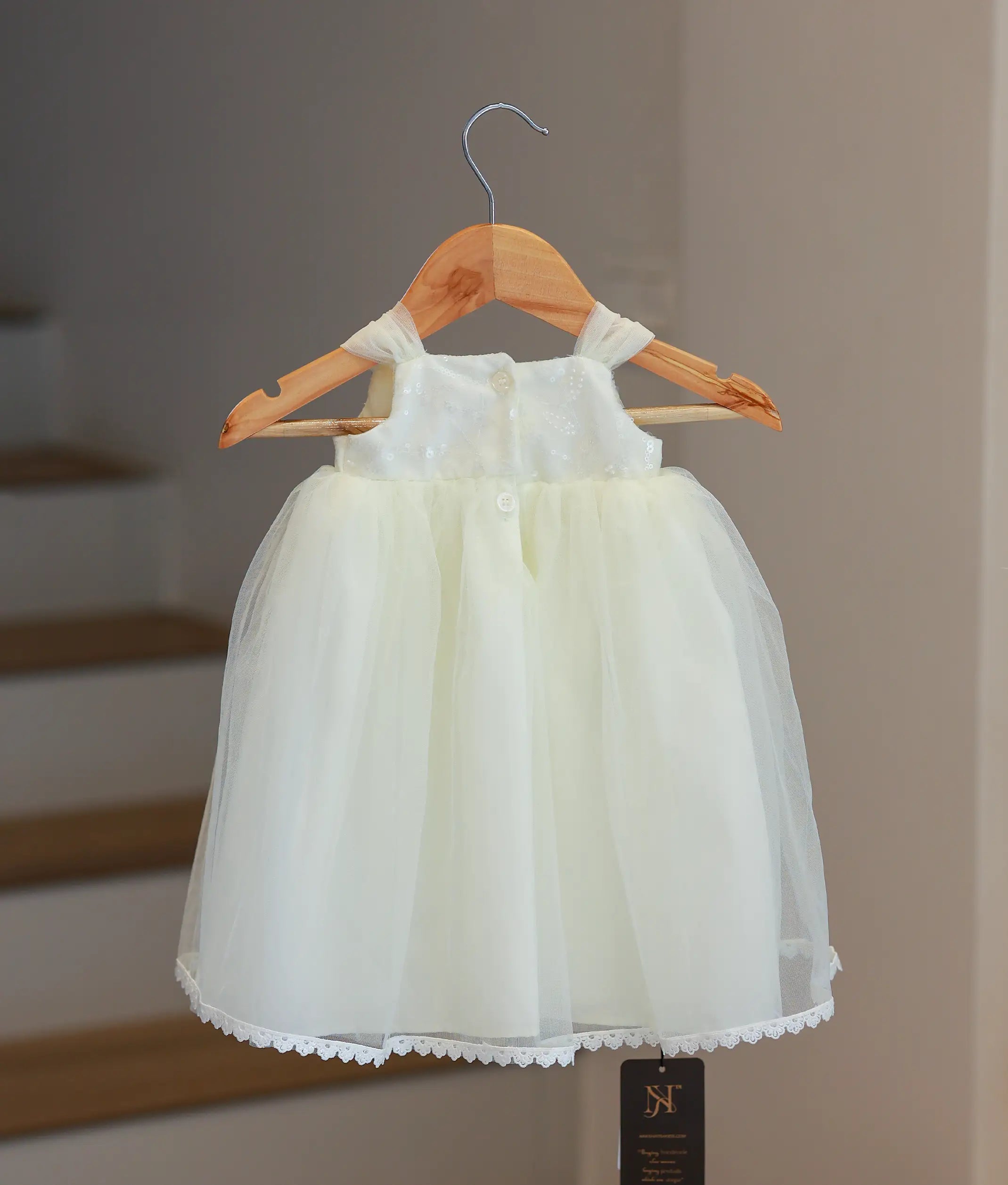 Back view of style 5585 off-white baptism gown showing the elegant fabric bow and layered tulle skirt finish.