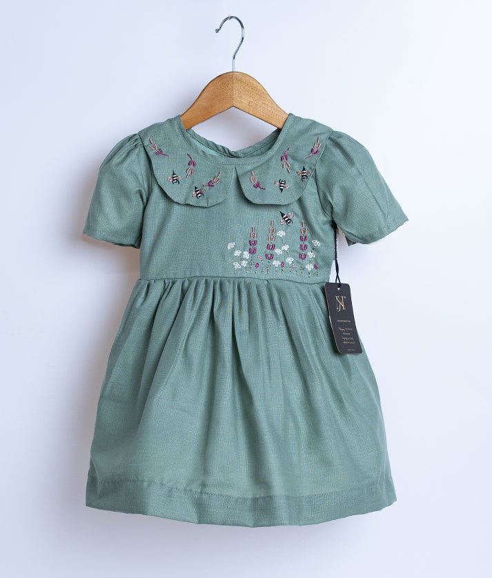 Pastel green cotton frock displayed on a hanger.