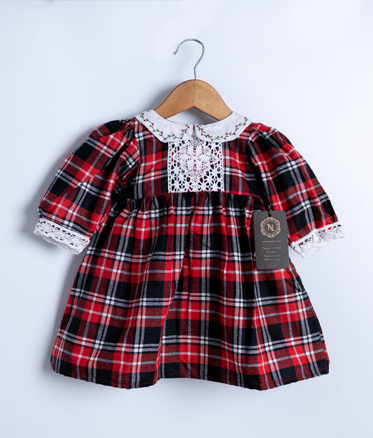 A red check cotton christmas frock hanging on a hanger against a white background.