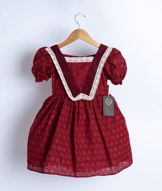 A maroon colored frock displayed on hanger.