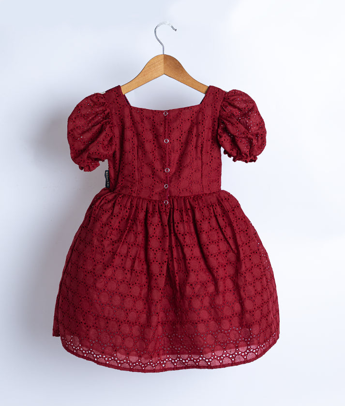 Back view of an maroon colored frock displayed on hanger.