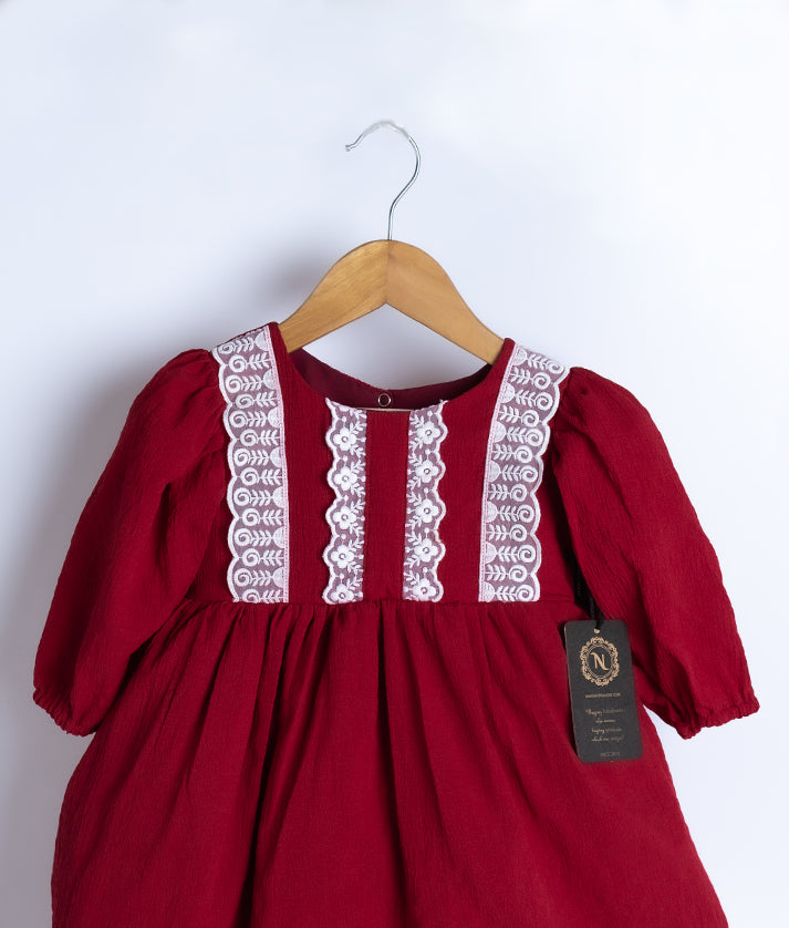 Close view of an maroon georgette christmas frock displayed on a hanger.