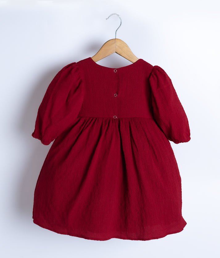 Back view of an maroon georgette christmas frock displayed on a hanger.