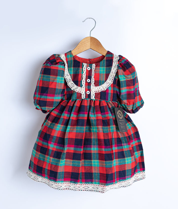 A red cotton checked christmas frock displayed on a hanger. 
