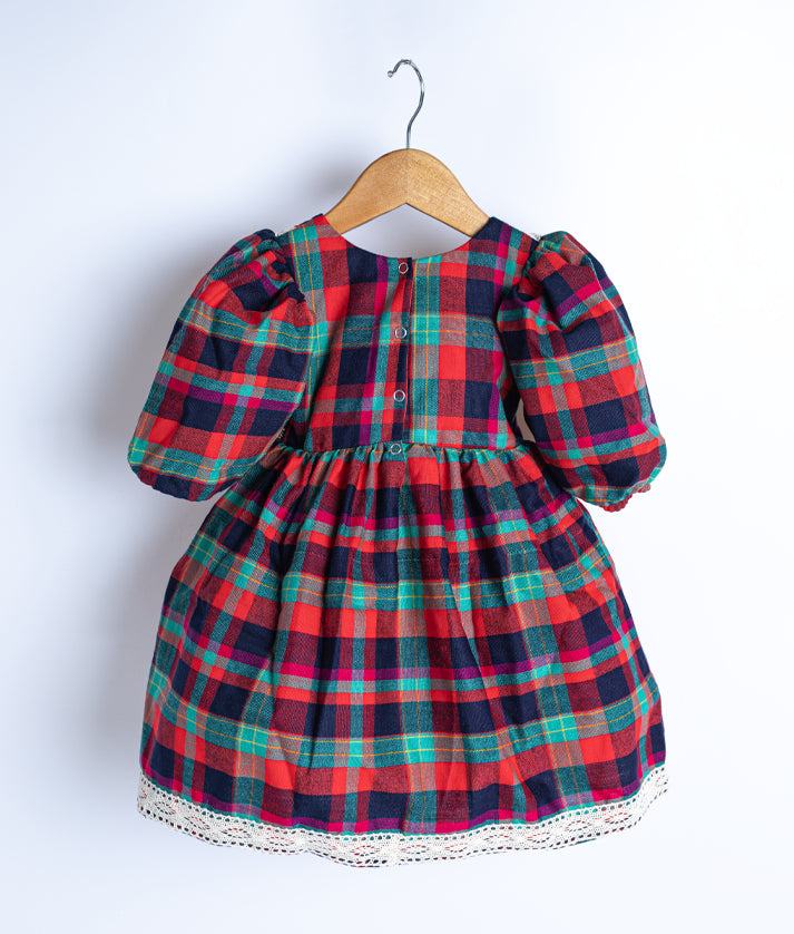 Back view of an red cotton checked christmas frock displayed on a hanger. 