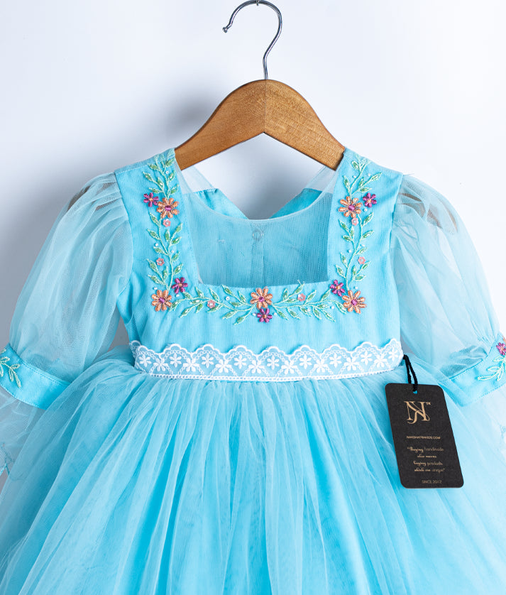 Sky blue net frock for baby girl with floral embroidery and puff sleeves, birthday or festive dress on wooden hanger against white background.