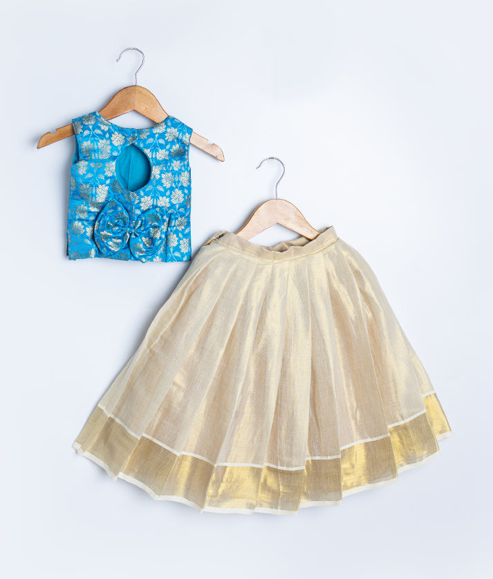 A kids ethnic wear set featuring a sleeveless blue brocade blouse with golden floral patterns and a gold flared skirt with sheer overlay, displayed on hangers.