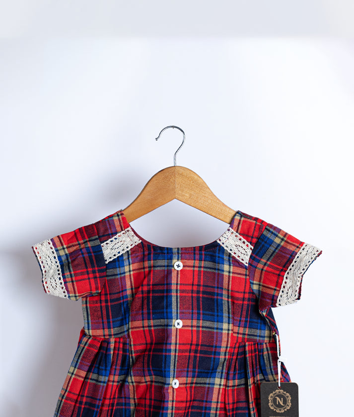 Close view of an red and white checkered cotton frock displayed on a hanger.
