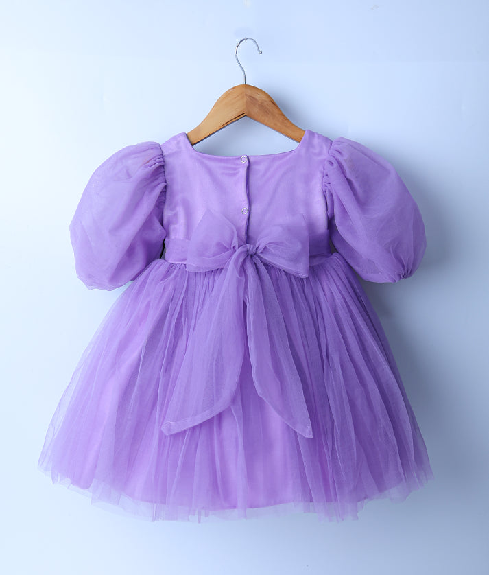 Back view of an lavender-colored tulle net frock displayed on a wooden hanger.