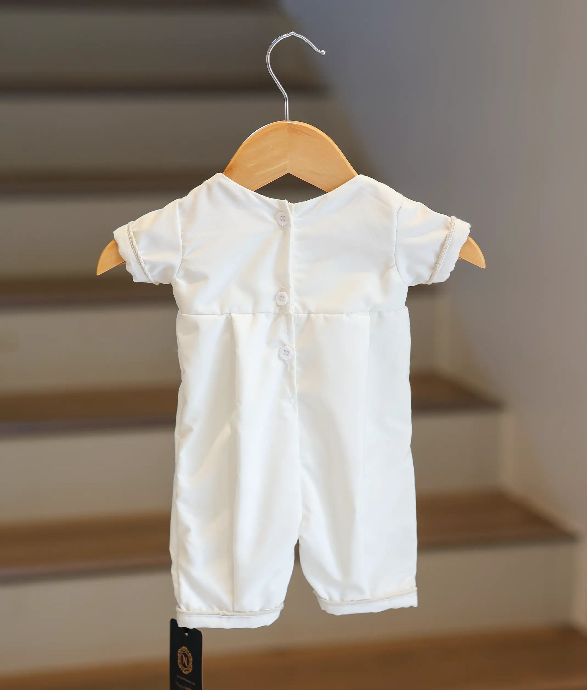 Back view of the white baptism romper showing the button closure.