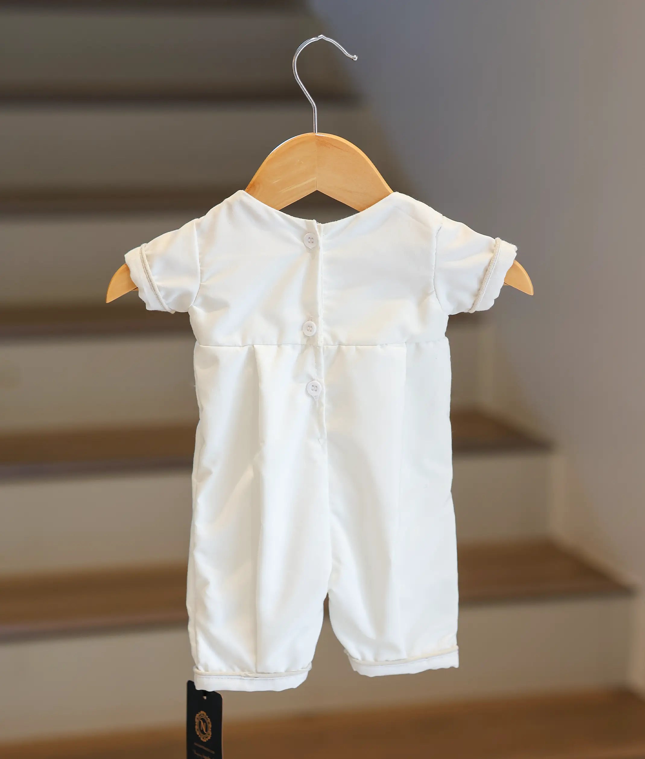 Back view of the white baptism romper showing the button closure.