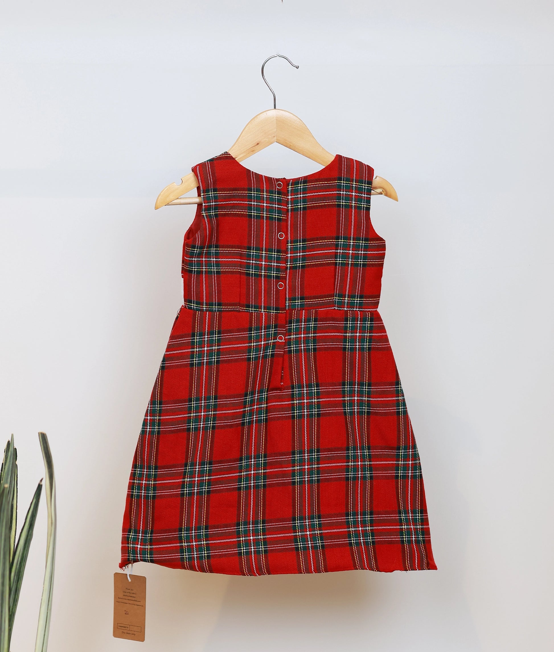 Back view of the baby girl Christmas frock showing the red and green check pattern and snap-button closures.