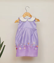 Front view of a lavender satin fish-cut birthday frock for baby girls featuring a white Peter Pan collar and horizontal floral hand-embellishment
