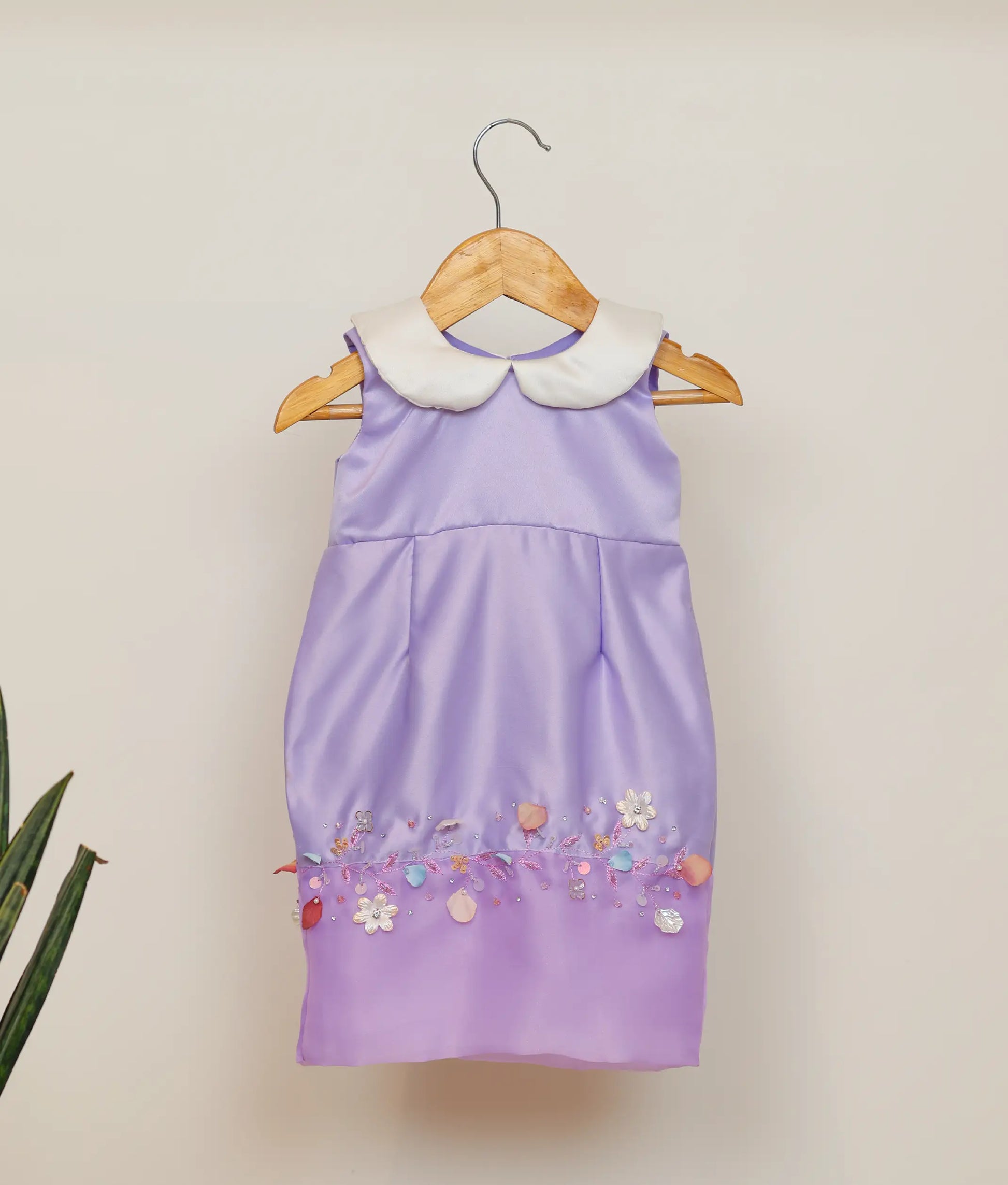 Front view of a lavender satin fish-cut birthday frock for baby girls featuring a white Peter Pan collar and horizontal floral hand-embellishment